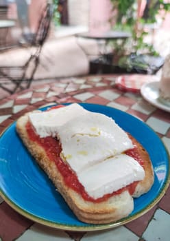 Cottage cheese and tomato toast over glazed tile mosaic table. Moroccan style background