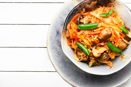 Cabbage stewed with mushrooms and carrots. Lenten food. Copy space, recipe place
