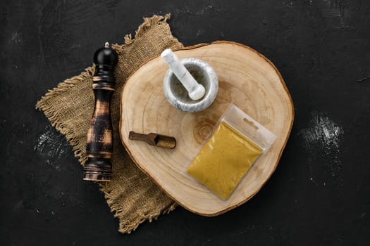 Wooden cross section with curry in plastic package and stone mortar and mill