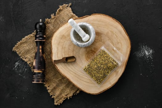 Wooden cross section with lemon pepper in plastic package and stone mortar and mill