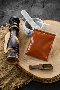 Wooden cross section with chilli pepper in plastic package and stone mortar and mill