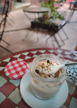 Spoonful of yogurt with muesli from glass jar. QR code sticker over glazed tile mosaic table
