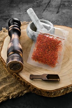 Wooden cross section with saffron in plastic package and stone mortar and mill