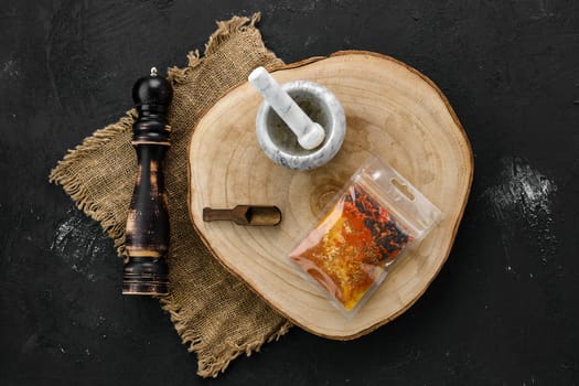 Wooden cross section with a set of spices for pilaf in plastic package and stone mortar and mill