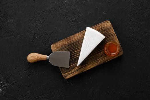 Piece of soft brie or camembert cheese on cutting board