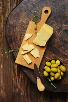 Overhead view of triangular piece of parmesan cheese on wooden cutting board