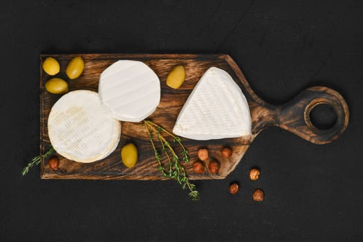 Top view of cheese platter. Assortment of brie and camembert cheese on wooden cutting board.