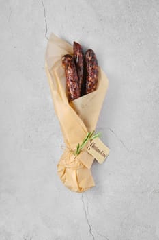 Overhead view of dried sausage made of venison spicy meat and lard in wrapping paper