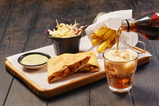 Pouring cola in a glass. Fast food snack concept.