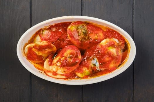 Overhead view of lamb dumplings with spicy tomato sauce baked in oven