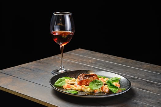 Roasted salmon fillet with bulgur with glass of rose wine on a table