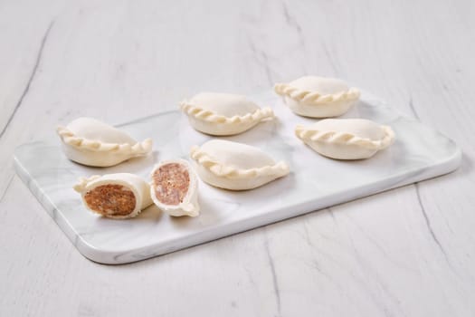 Frozen dumplings stuffed with beef meat and provencal herbs on marble serving plate