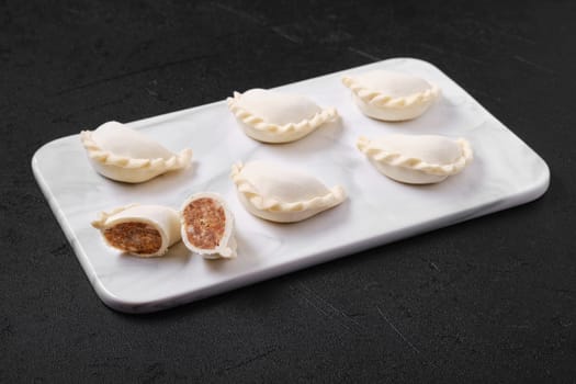 Frozen dumplings stuffed with beef meat and provencal herbs on marble serving plate