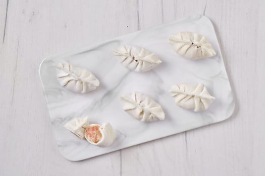 Top view of frozen dumplings stuffed with liver and provencal herbs on marble serving plate