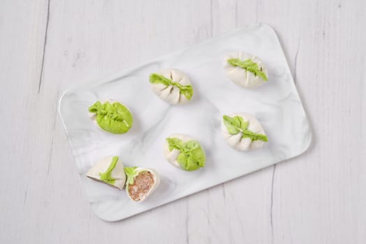 Top view of frozen dumplings stuffed with pork meat and provencal herbs on marble serving plate