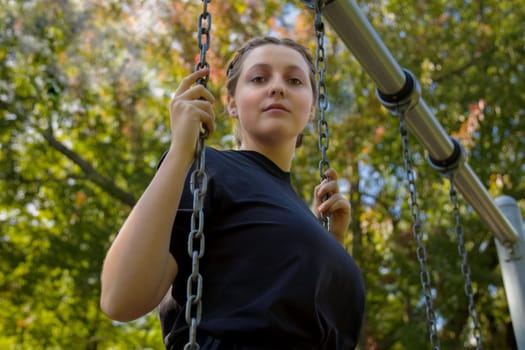 girl in a park young woman holding chains standing in a swing at the park active playing lifestyle