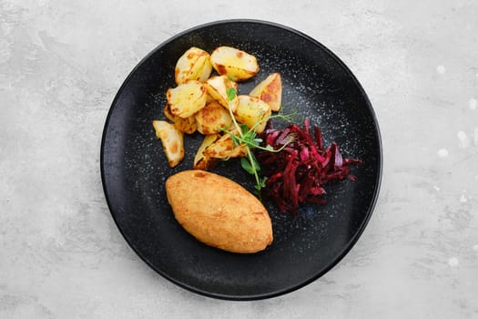 Kiev or pozharskaya cutlet served with fried potato and beet on a plate, top view