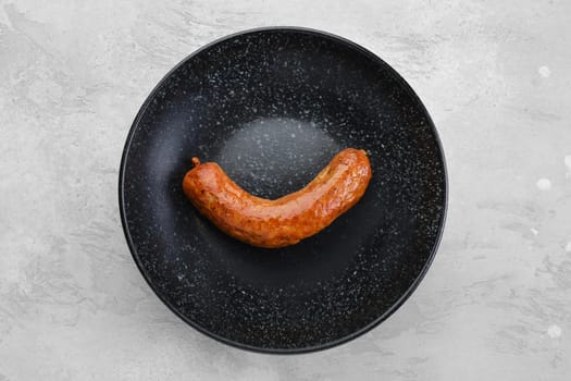Fried bavarian sausage on a plate, top view
