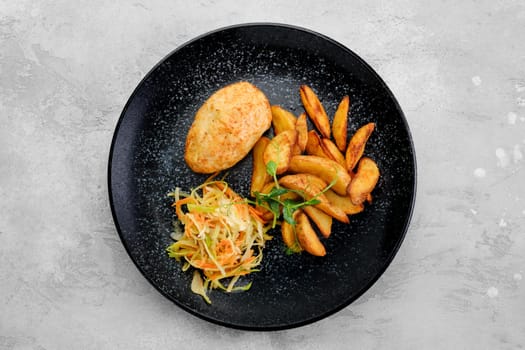Kiev cutlet stuffed with cheese and butter served with fried potato wedges and pickled cabbage, top view