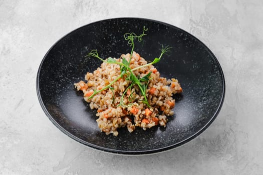 Garnish to the main dish - buckwheat porridge with slices of fried carrot on a plate