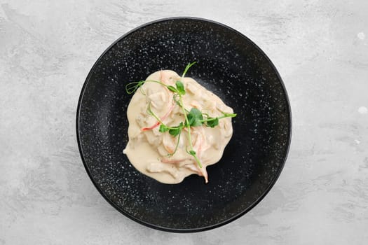 Pieces of chicken meat with bell pepper and creamy white sauce on a plate, top view