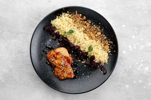 Fried chicken meat with teriyaki sauce and pearl barlew on a plate, top view