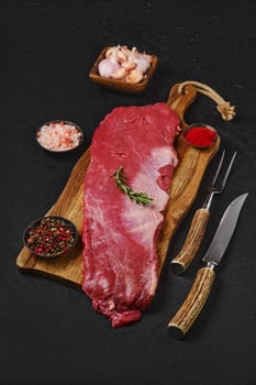 Top view of raw ribeye cap roll with spice on wooden cutting board