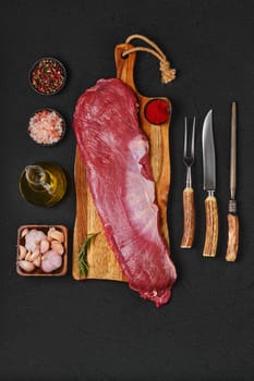 Top view of raw ribeye cap roll with spice on wooden cutting board