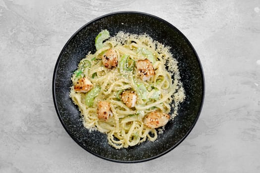 Spaghetti with chuka salad, fried zander fillet and bechamel sauce on a plate, top view