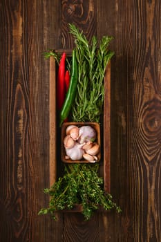 Overhead view of wooden cutting board with fresh rosemary and spices for piquant sauce or marinade on wooden kitchen table