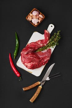 Composition with raw beef whole tenderloin on black background