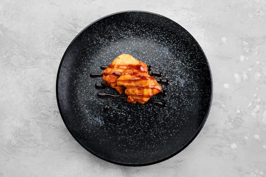 Fried chicken meat with teriyaki sauce on a plate, top view