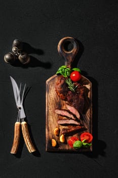 Overhead view of beefsteak spider fried in cast-iron pan, served on wooden cutting board with tomato and basil