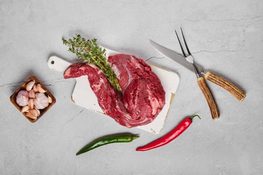 Raw beef whole tenderloin with herbs and spice on concrete background