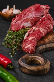 Closeup view of raw beef whole tenderloin with herbs and spice on black background
