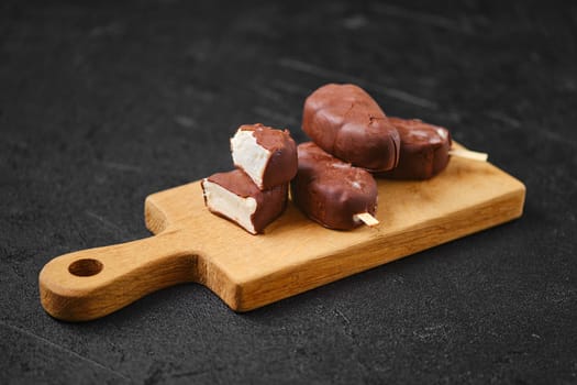 Homemade curd bars in chocolate on wooden board (soft focus photo)