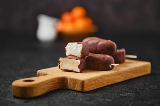 Homemade curd bars in chocolate on wooden board (soft focus photo)