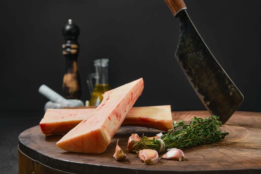 Large beef bone marrow chopped on half with spice and herbs on wooden stump