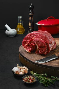 Raw beef neck with thyme, garlic and spice on wooden stump