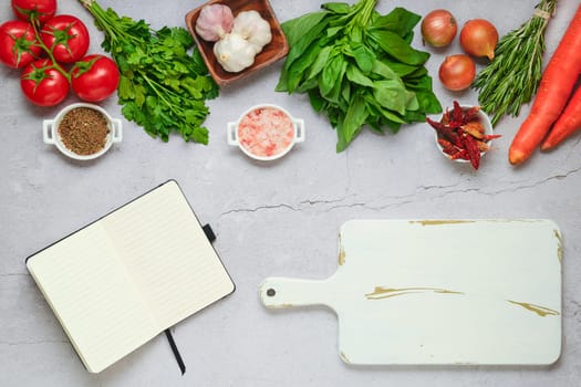 Diet food concept of healthy eating. Opened notebook next to cutting board and fresh vegetables and herbs