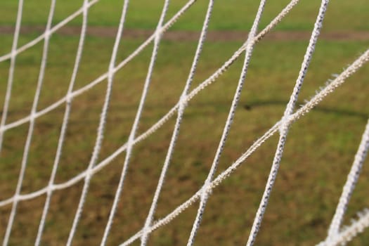 The grid from the old football goal close-up on the background of the football field.