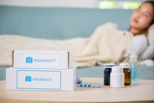 Asian young woman cold sick she sleeping and resting on sofa after take pills at home, beautiful female health problem use pharmacy kit box delivery service from hospital, delivery pharmacy concept