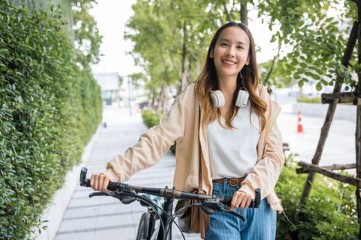 Lifestyle Asian young woman walking alongside with bicycle on summer in countryside outdoor, Happy female smiling walk down the street with her bike on city road, ECO environment, healthy travel