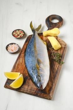 Whole fresh chinook on wooden cutting board with spice, lemon and ginger