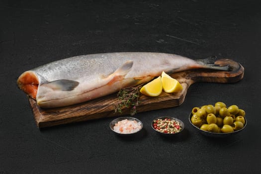 Headless fresh chinook on wooden cutting board with spice and lemon