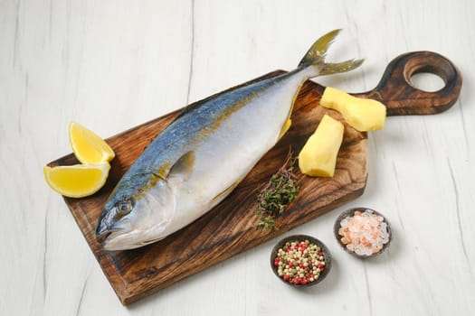 Whole fresh chinook on wooden cutting board with spice, lemon and ginger