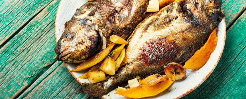 Delicious fried fish dorada with fruits and spices.