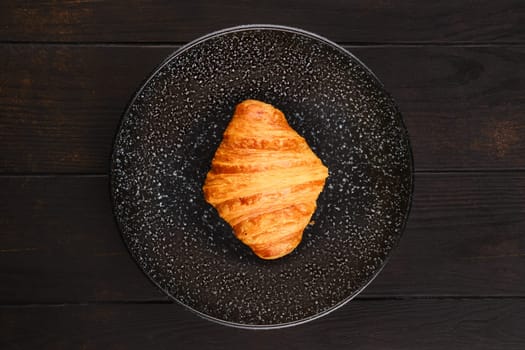Top view of freshly baked big croissant on a plate