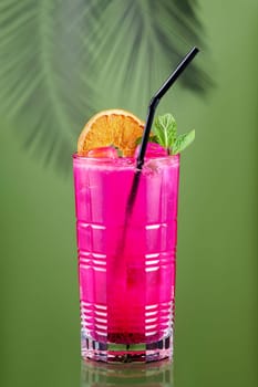 Cold lemonade with dragon fruit, orange and coconut juice on green background