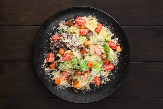 Caesar salad with fresh vegetables, croutons and grated cheese, top view